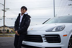 Preston leaning against white Porsche Cayenne