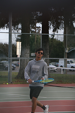 Preston wearing gray sweatshirt running on tennis court holding Babolat Pure Drive